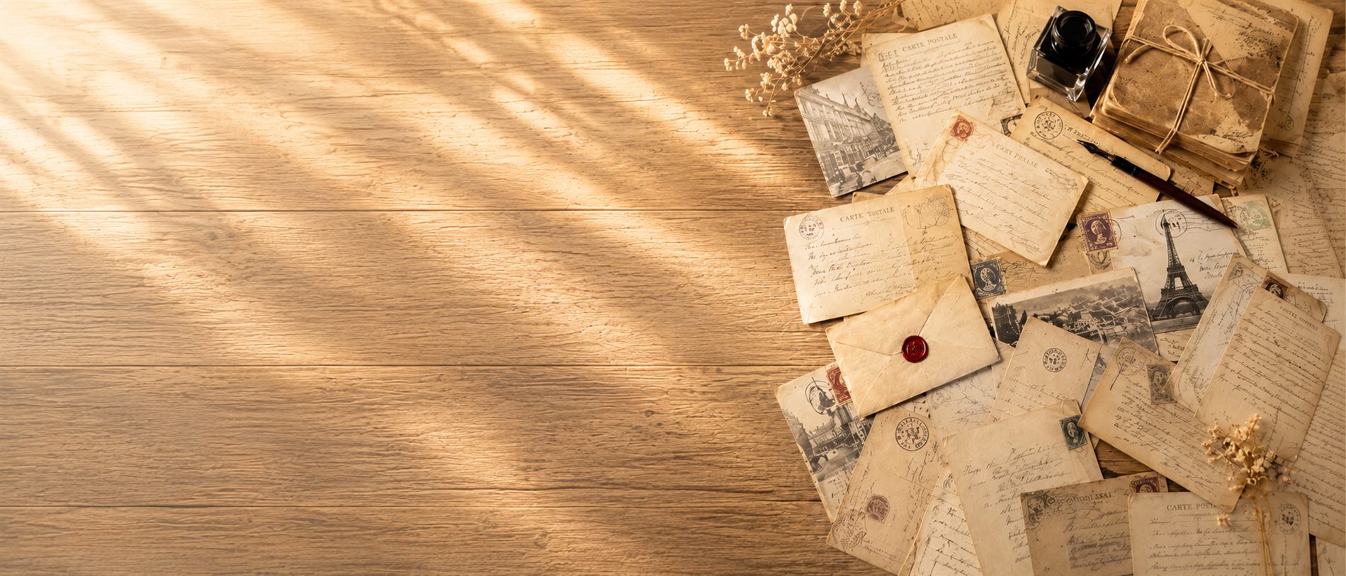 Alte handschriftliche Briefe, Postkarten, ein Tintenfass und getrocknete Blumen auf einem Holztisch